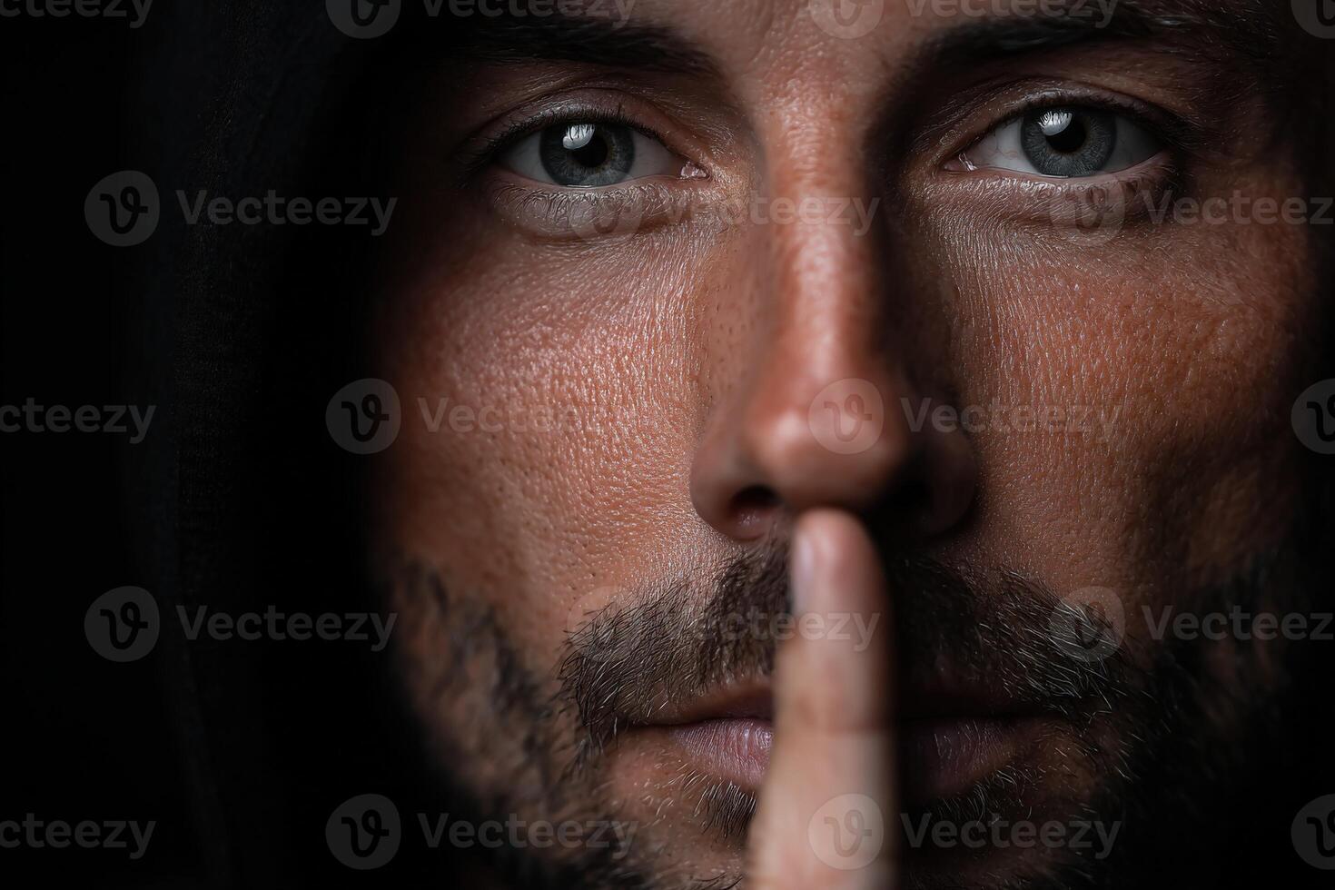 Mysterious man with a shushing gesture and intense gaze in low light photo