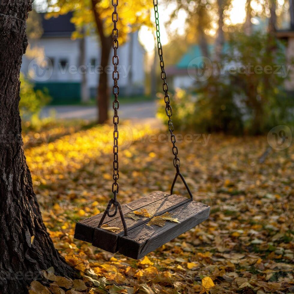 Wooden swing hanging from a tree surrounded by autumn leaves photo