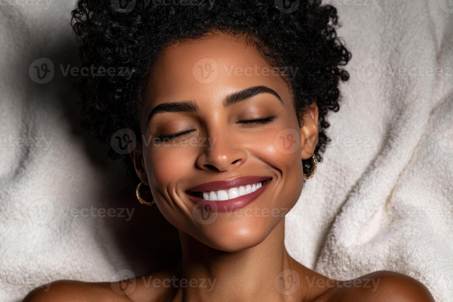 Smiling woman with curly hair enjoys relaxation on soft blanket photo