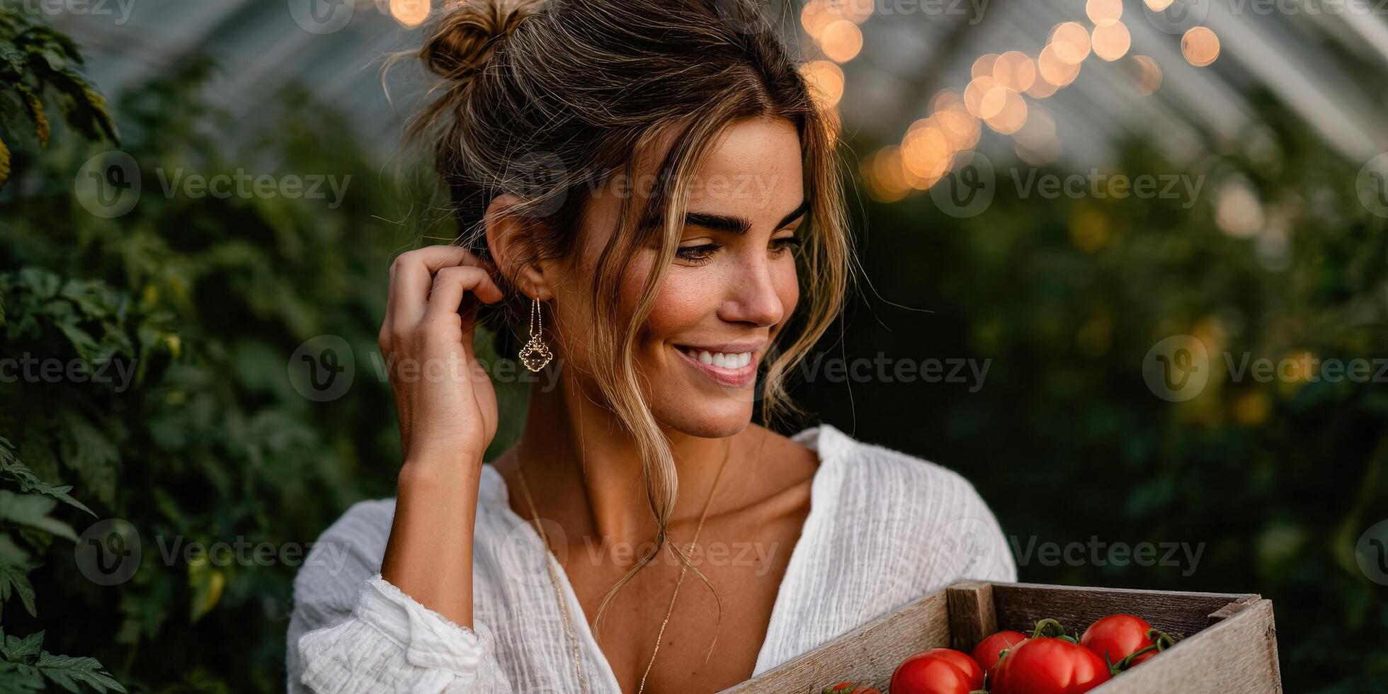 Smiling woman harvesting fresh tomatoes in a greenhouse at sunset photo
