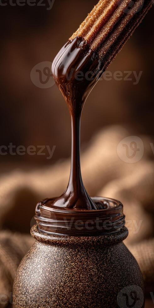 Churro dipped in rich chocolate sauce on a rustic table photo