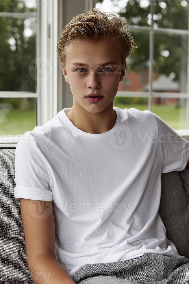 Young man sits on a couch by the window with serene expression photo
