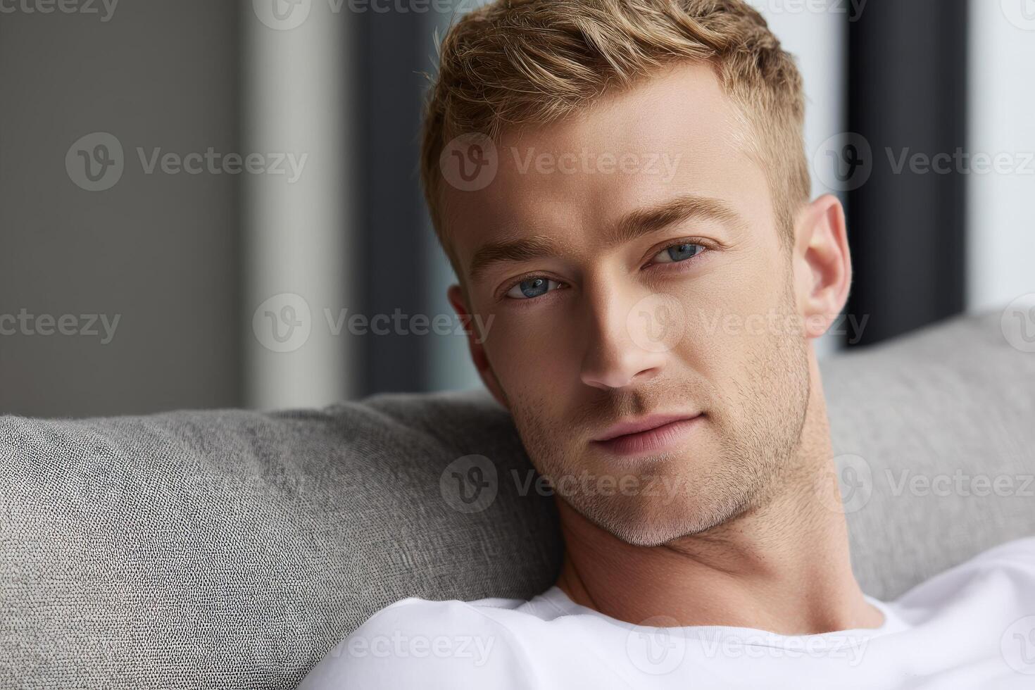 Young man relaxes on a couch in a modern indoor setting during daytime photo