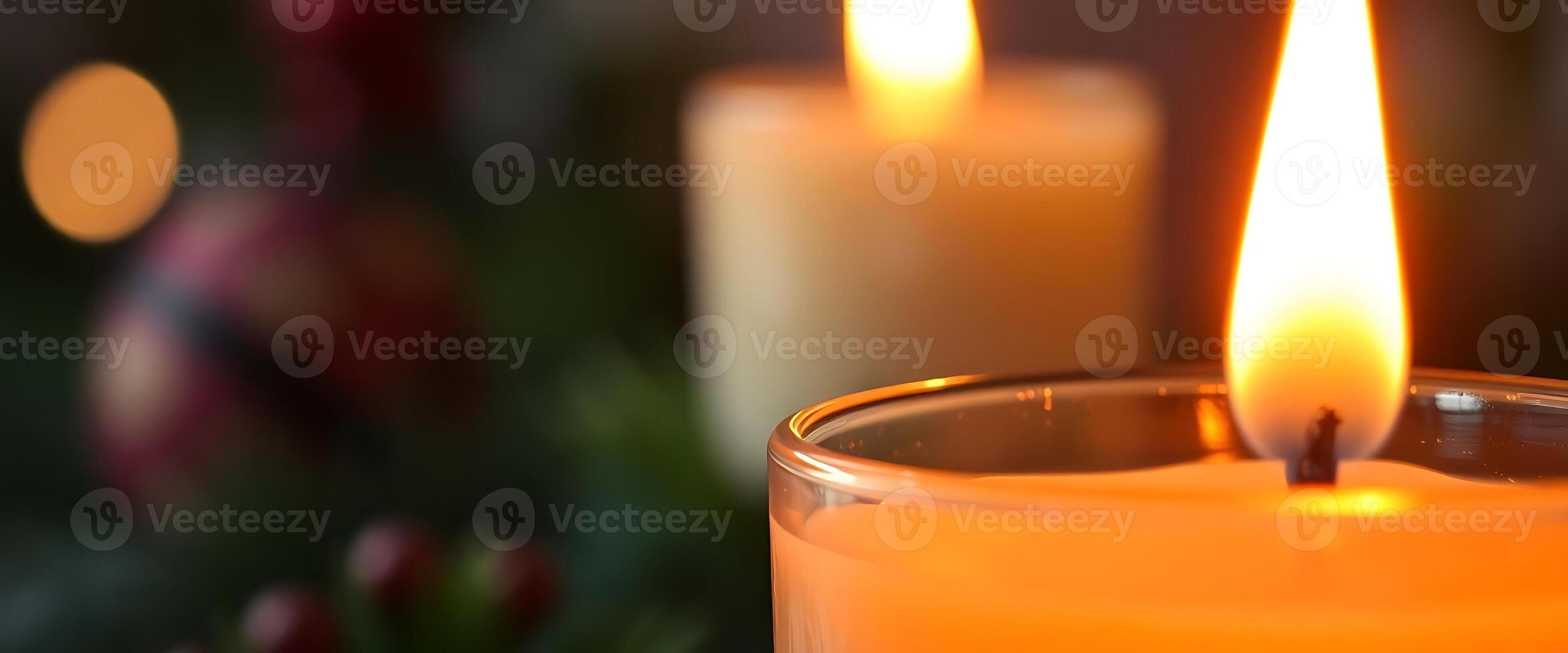 close up of a lit candle in front of a christmas tree photo