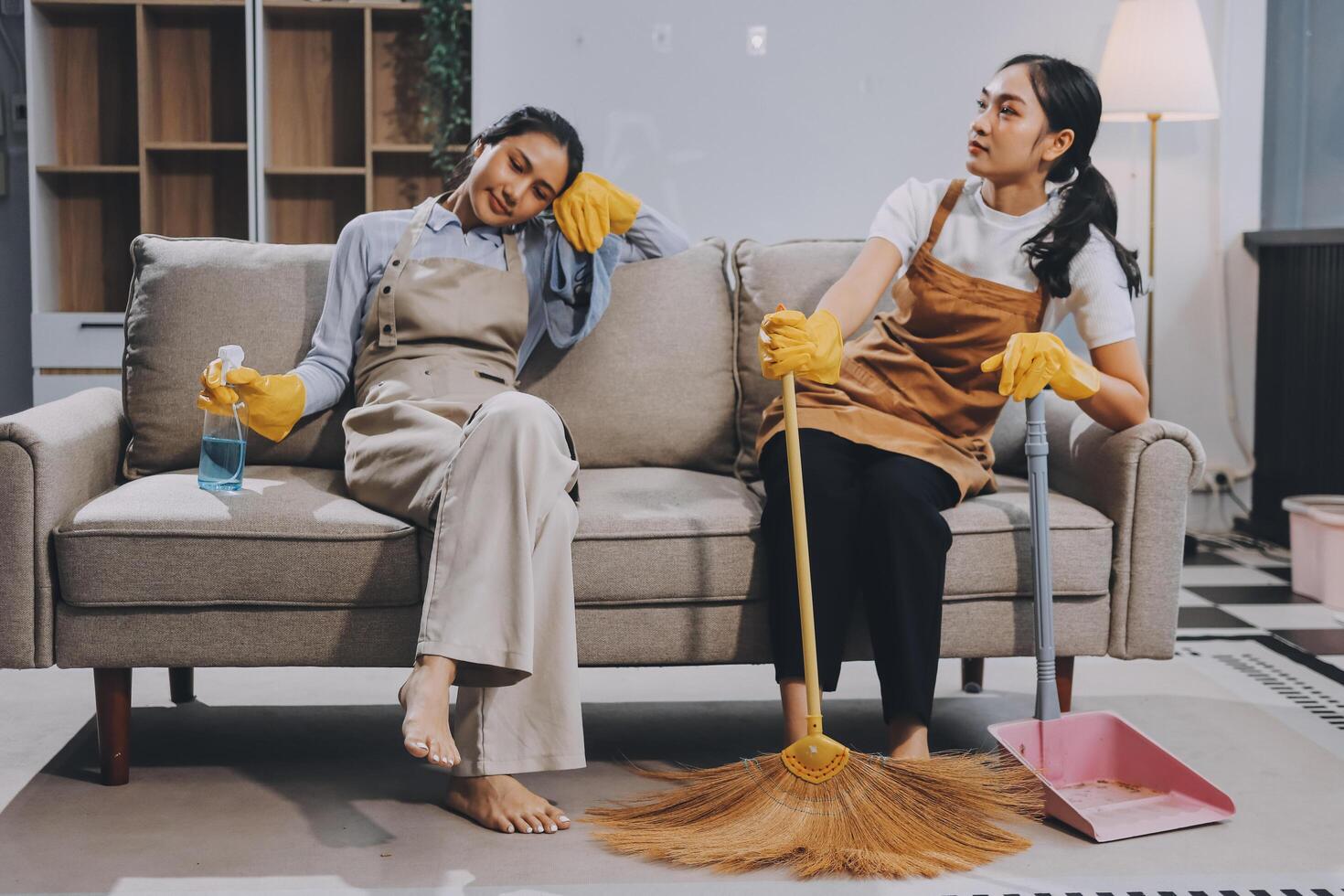 Two women sitting on a couch with a broom and mop photo