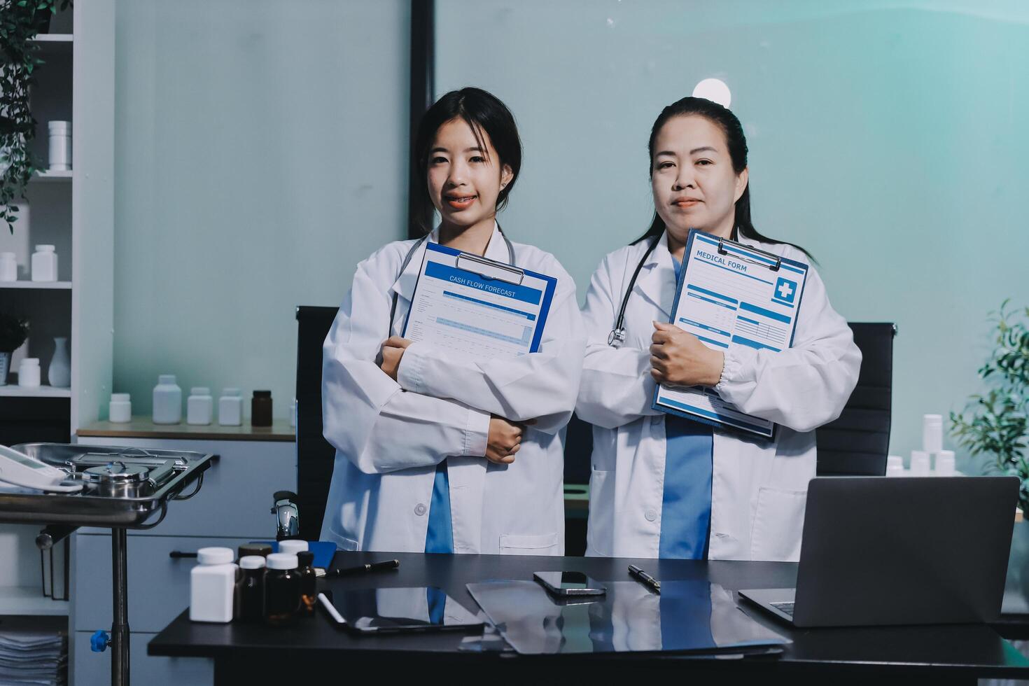Two female doctors holding folders in front of a desk photo