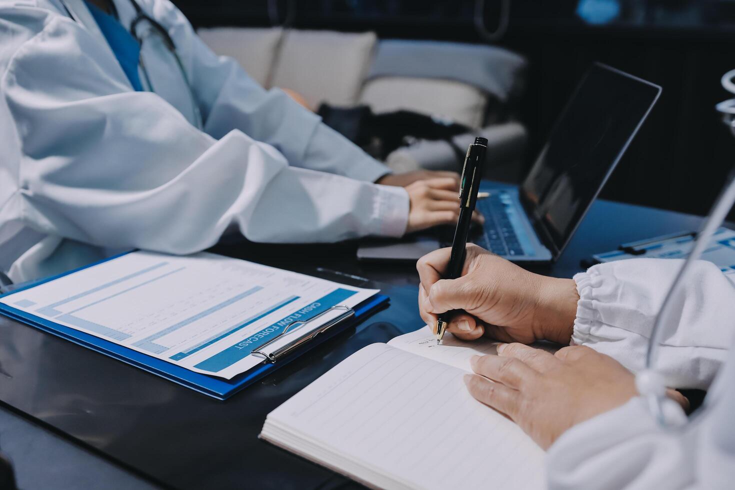 A doctor writing on a notebook while sitting at a desk photo