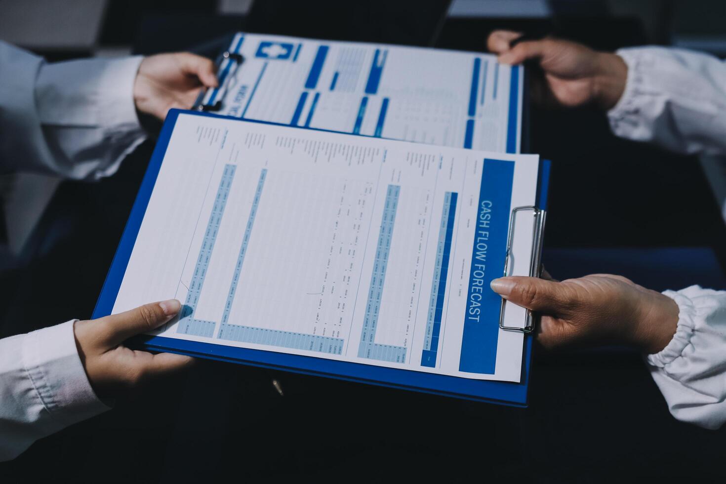 Two people holding blue folders with papers on them photo