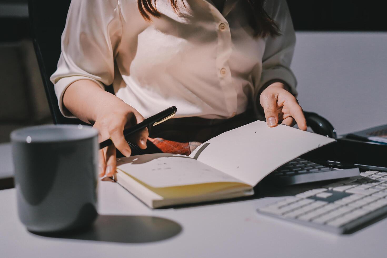 A woman is sitting at a desk with a notebook and a cup of coffee photo