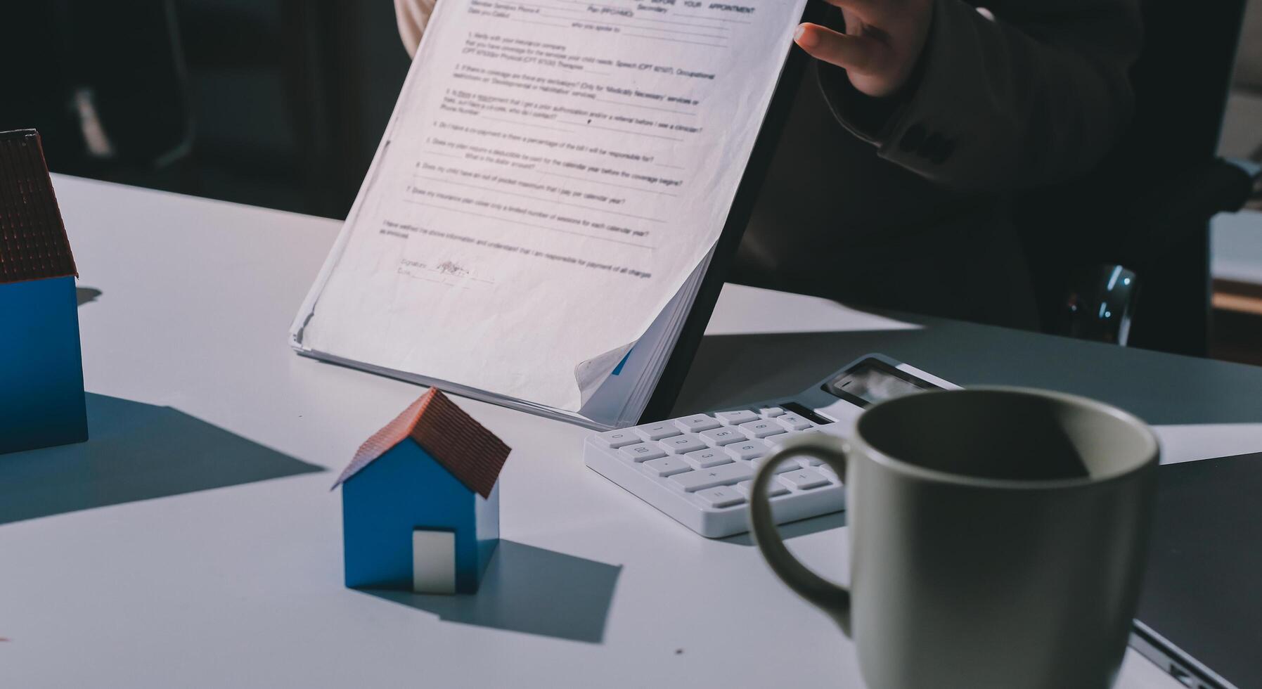 A person is holding a piece of paper with a house on it and a pen in her hand photo