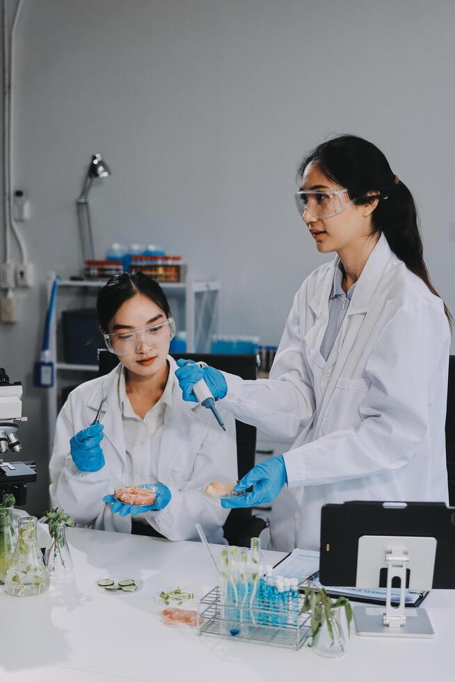 Two women in lab coats and gloves working on plants photo