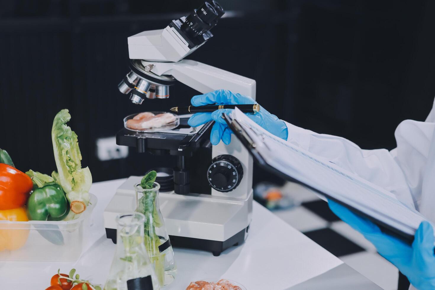 A person in a lab coat is holding a clipboard and looking at a microscope photo
