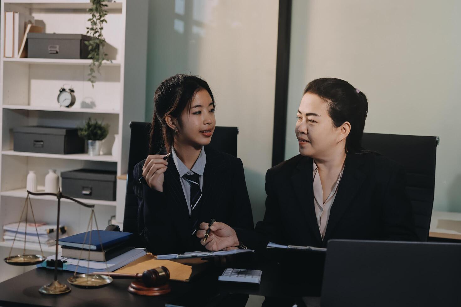 Two women in business attire sitting at a desk photo