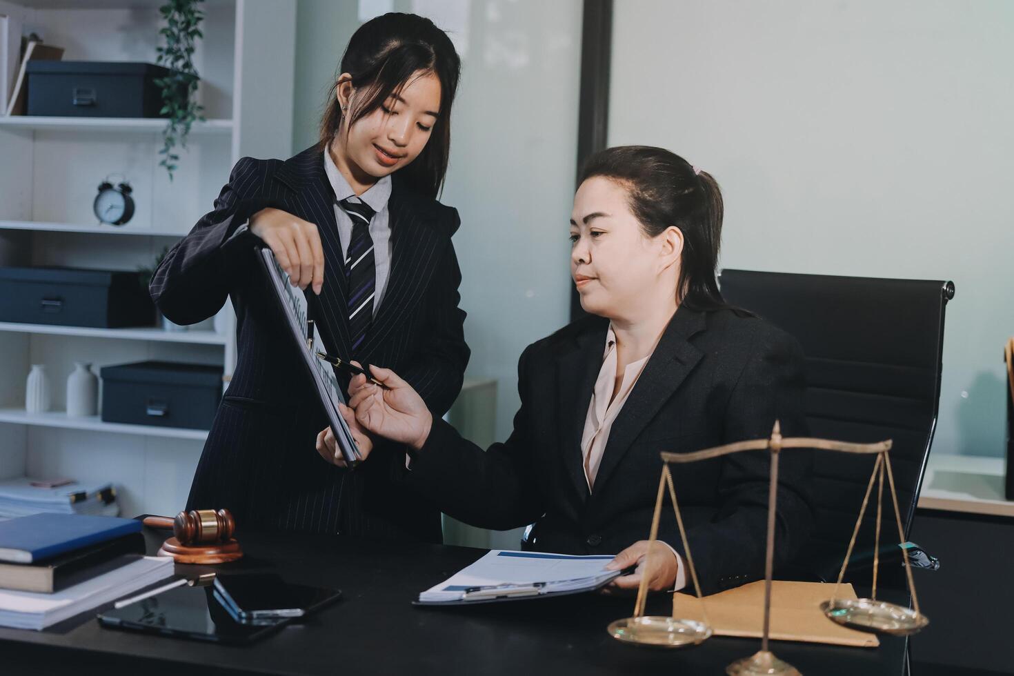 Two business women in suits standing at a desk with a scale photo