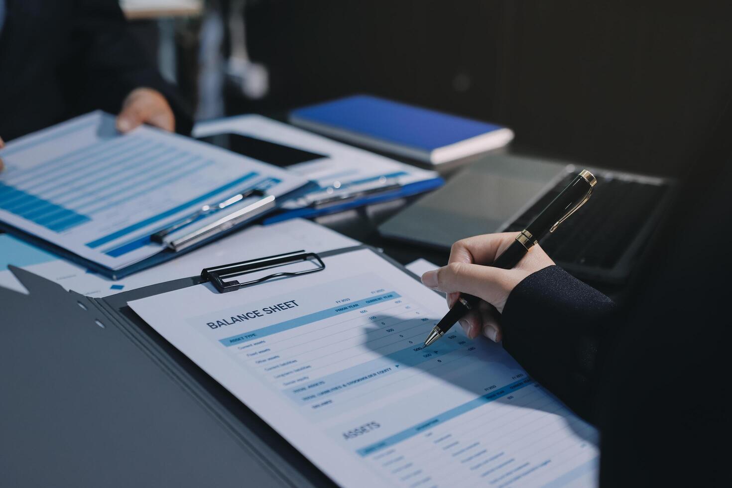 A person is writing on a document with a pen photo