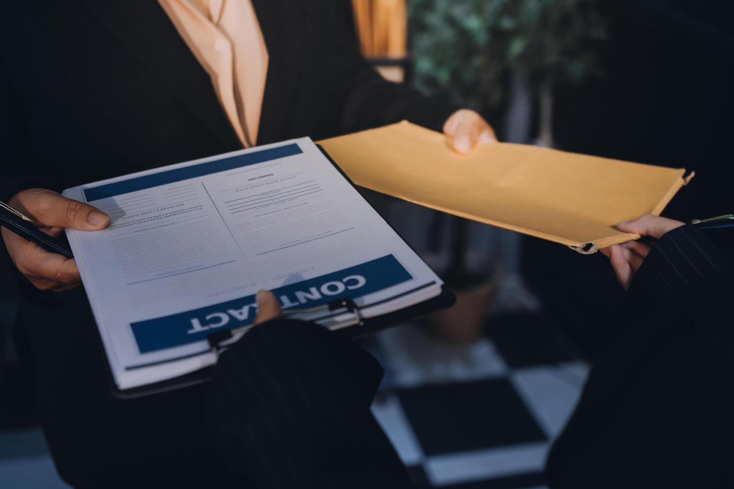 A businessperson handing over a document to another person photo