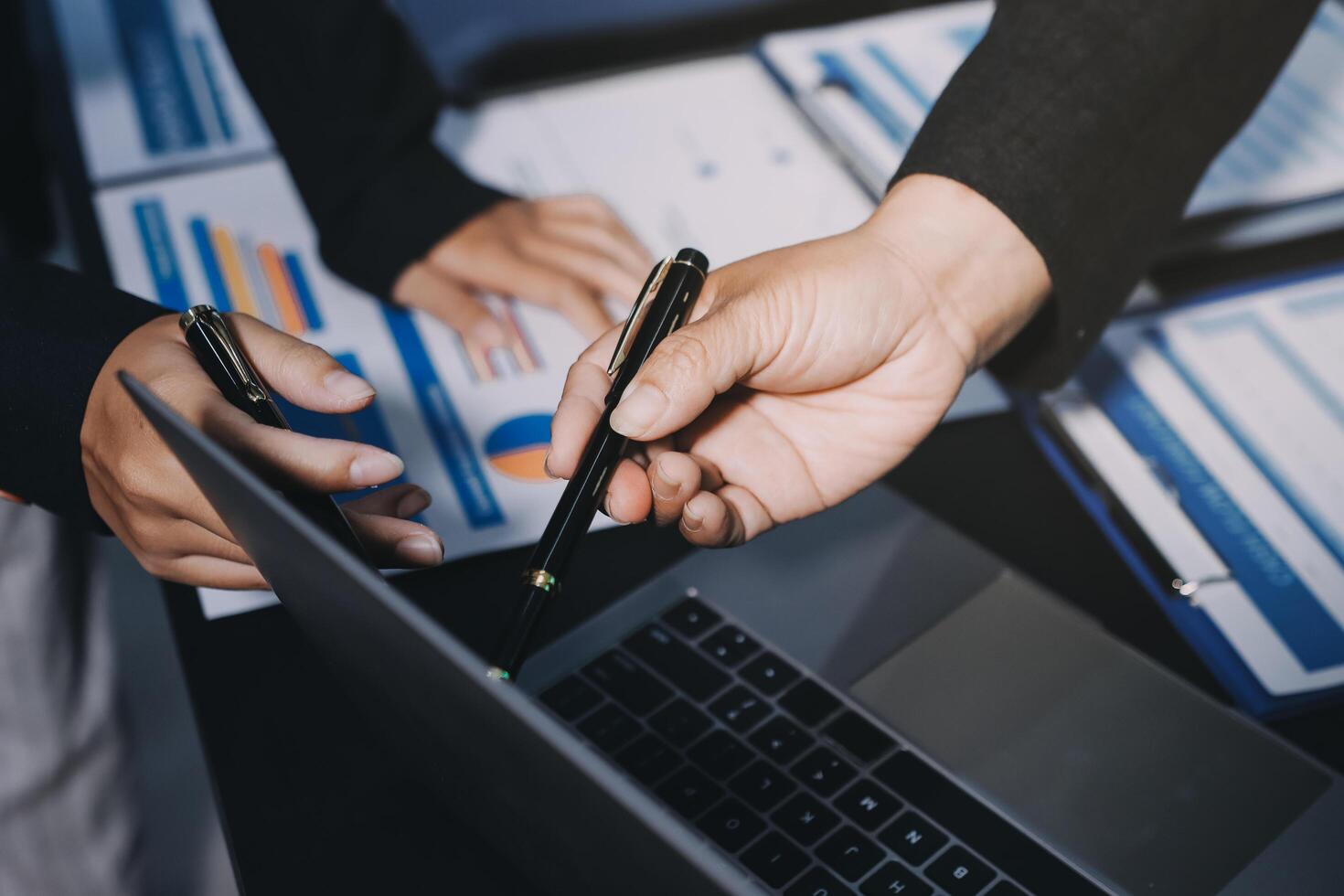 Business people using laptops and pen to write on papers photo