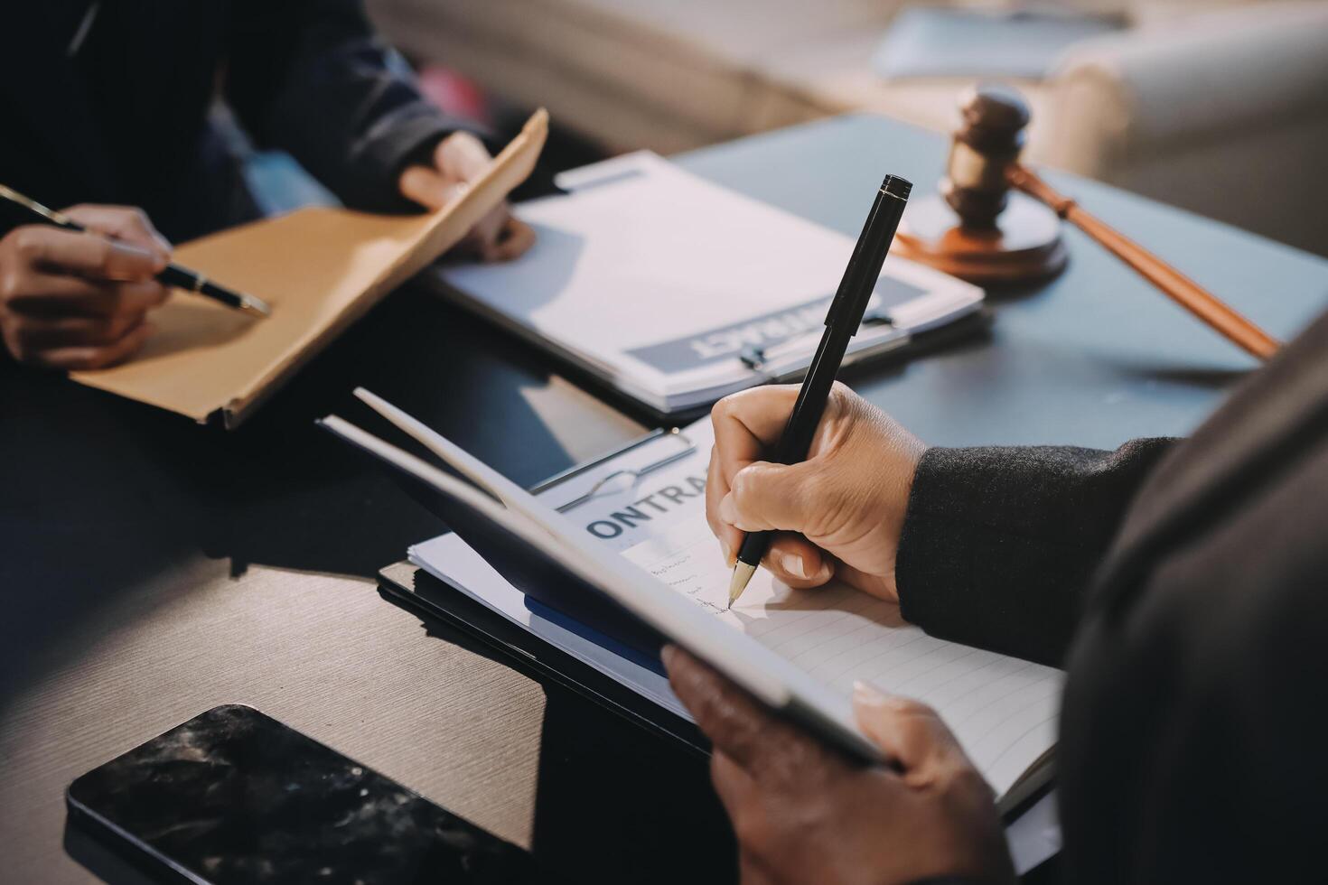 A lawyer writing on a notepad while a client sits at a desk photo
