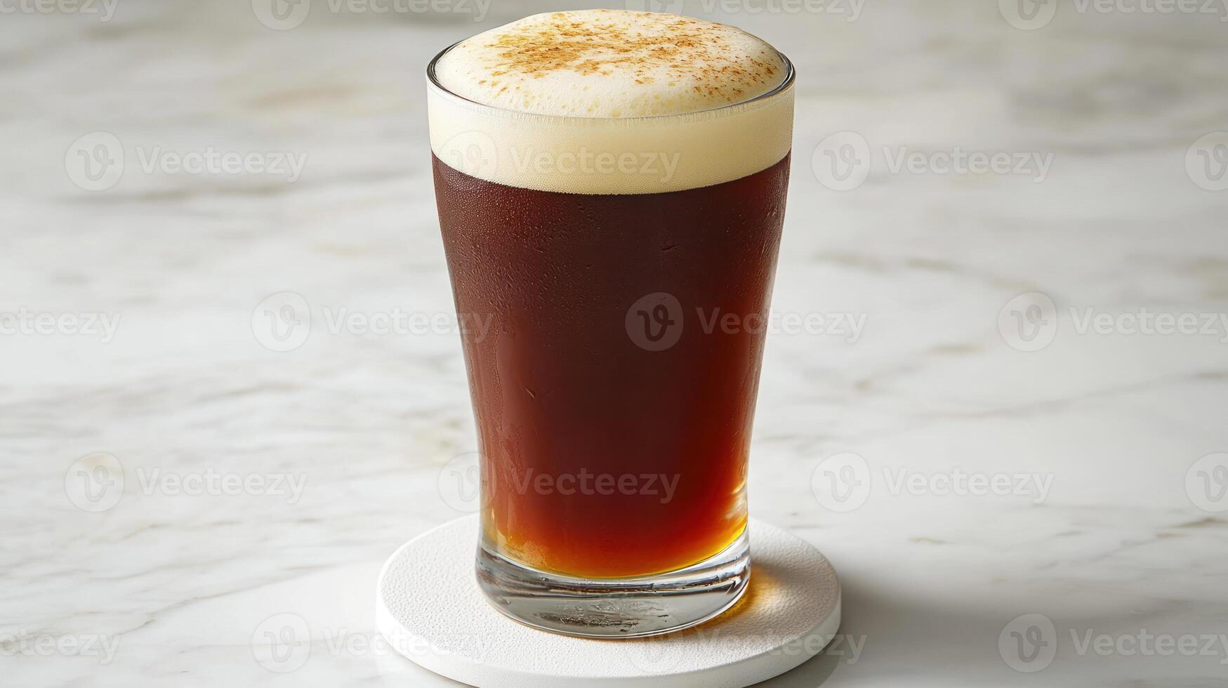 A tall glass of beer sitting on a marble surface photo