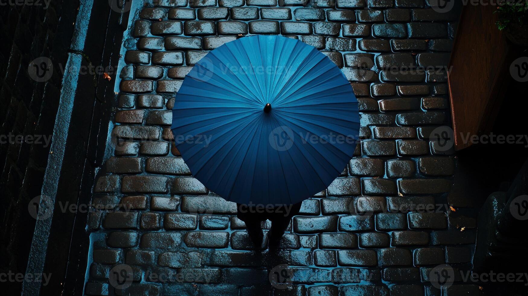A person walking down a cobblestone street with a blue umbrella photo