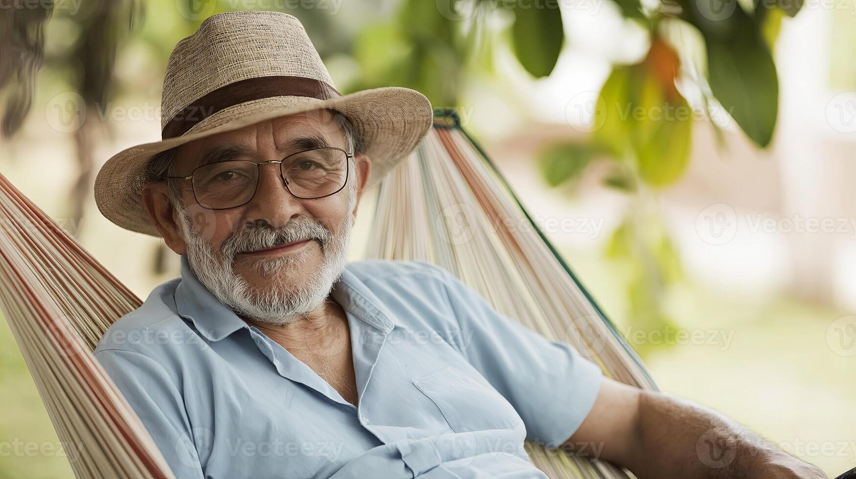 An older man in a hat and glasses sitting in a hammock photo