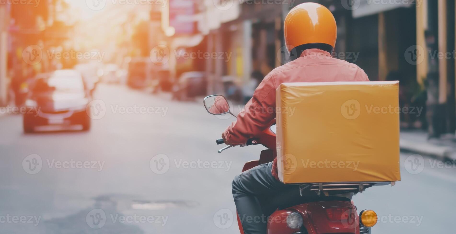 Delivery rider navigating a sunny city street during early evening hours while transporting a package on a motorcycle photo
