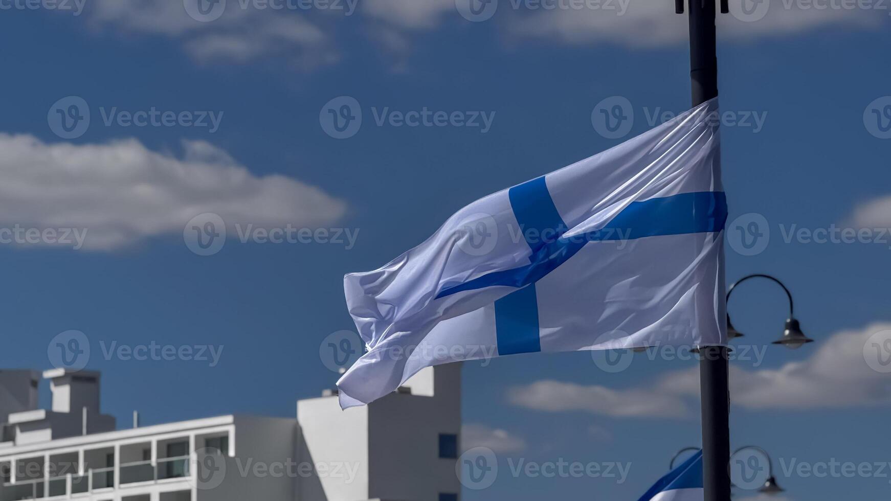 Flags of Cyprus and Greece flutter in the wind above modern white buildings under a vivid blue sky. photo