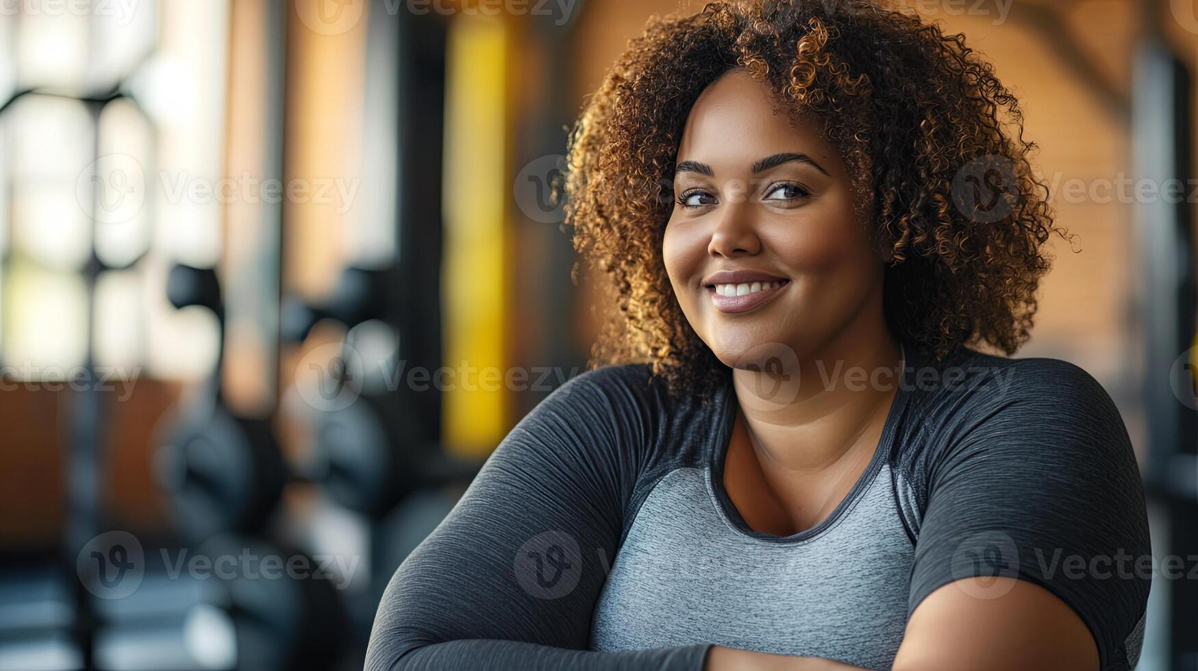 A woman with curly hair is smiling in a gym photo
