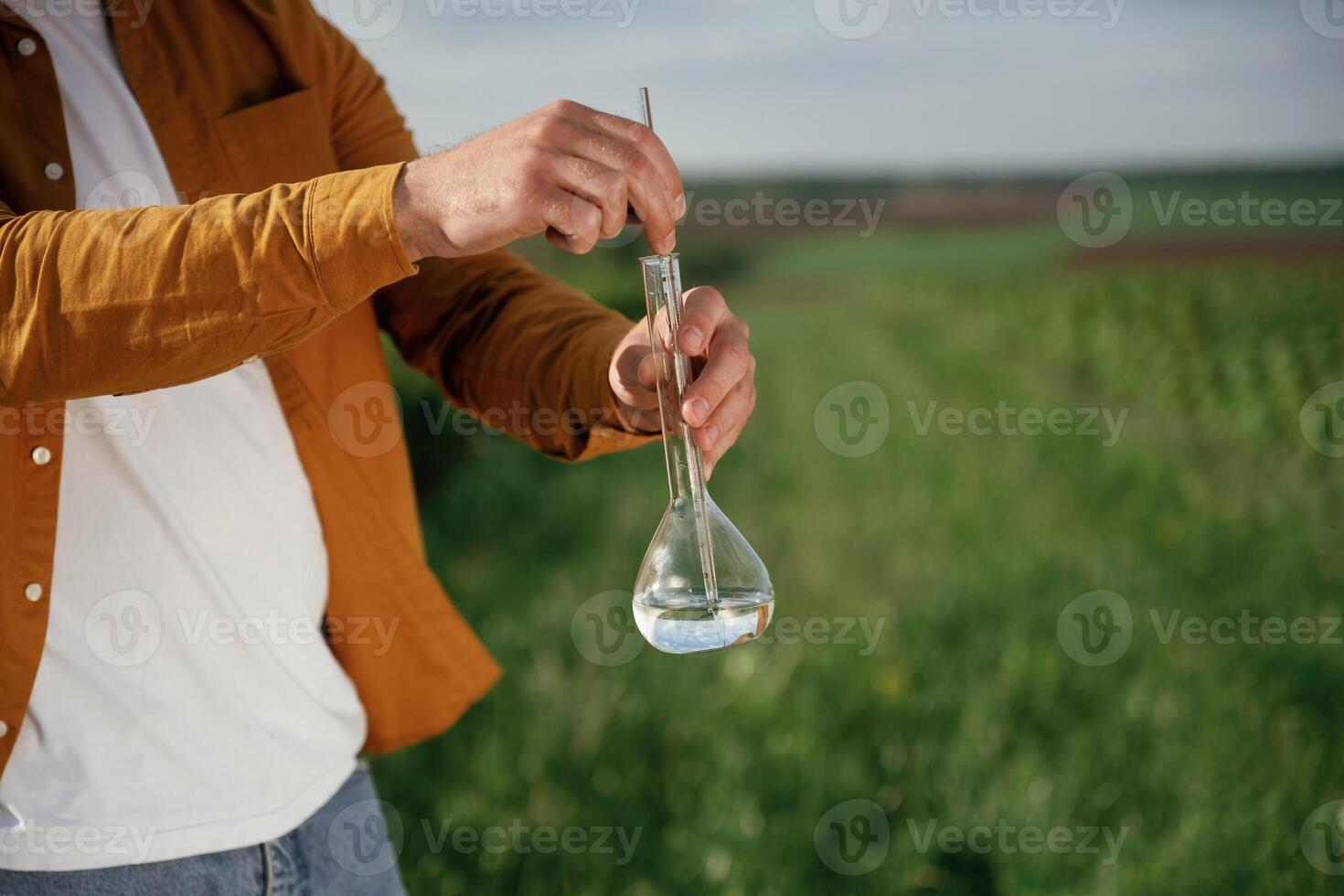 With test tube.... Close up view of man that is on the agricultural field at daytime photo