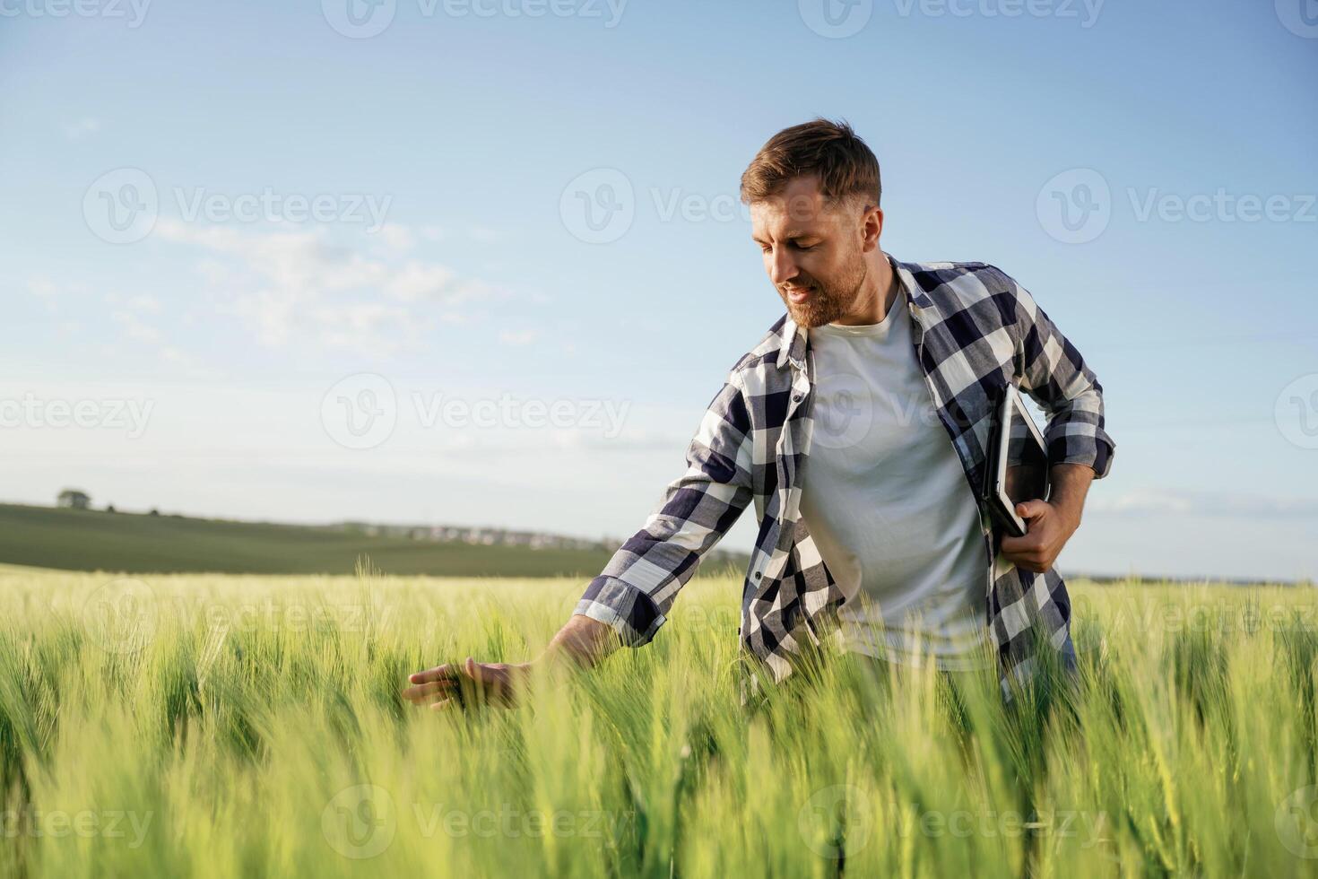 Black digital tablet in hands. Handsome man is on the agricultural field at daytime photo