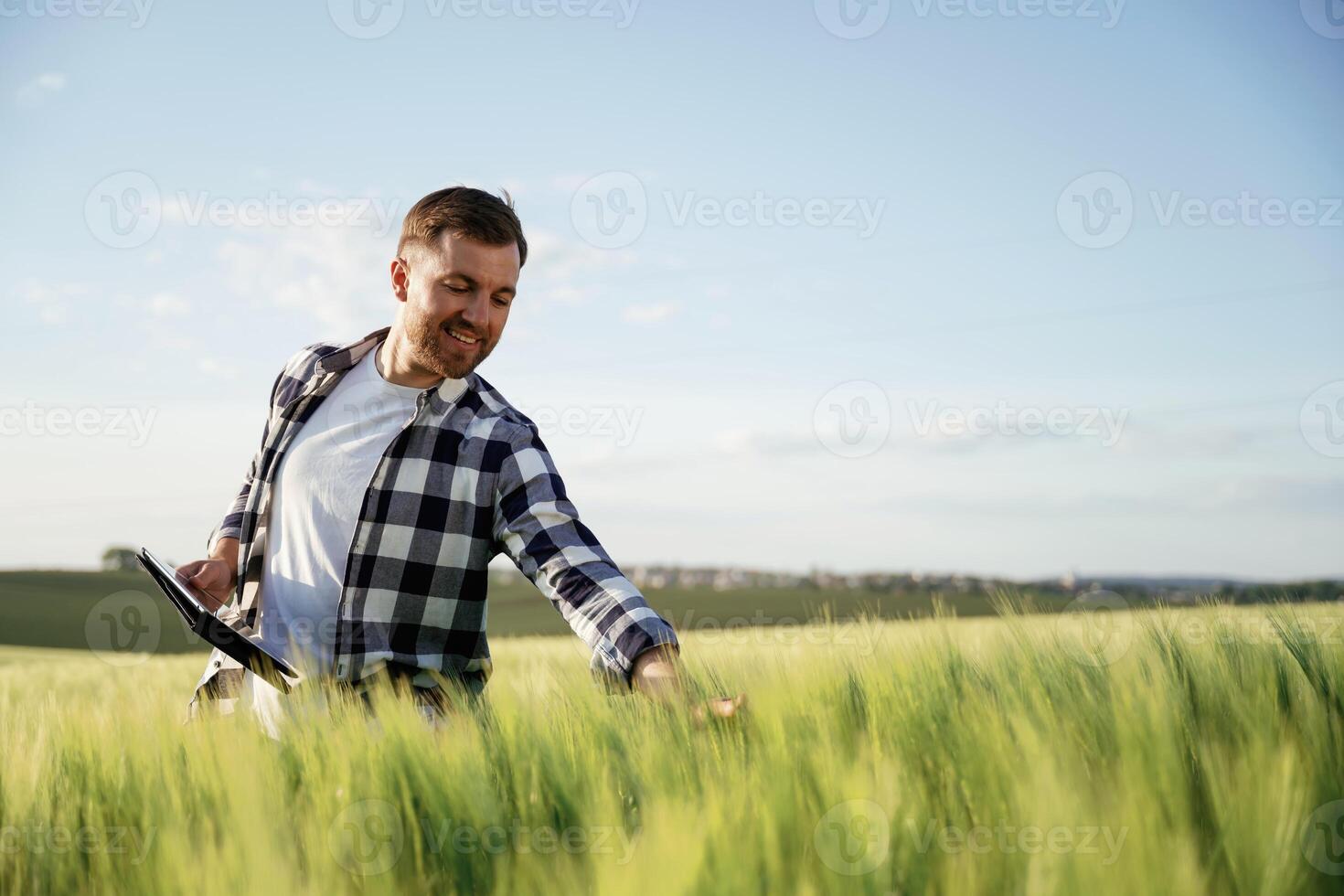 Black digital, tablet in hands. Handsome man is on the agricultural field at daytime photo