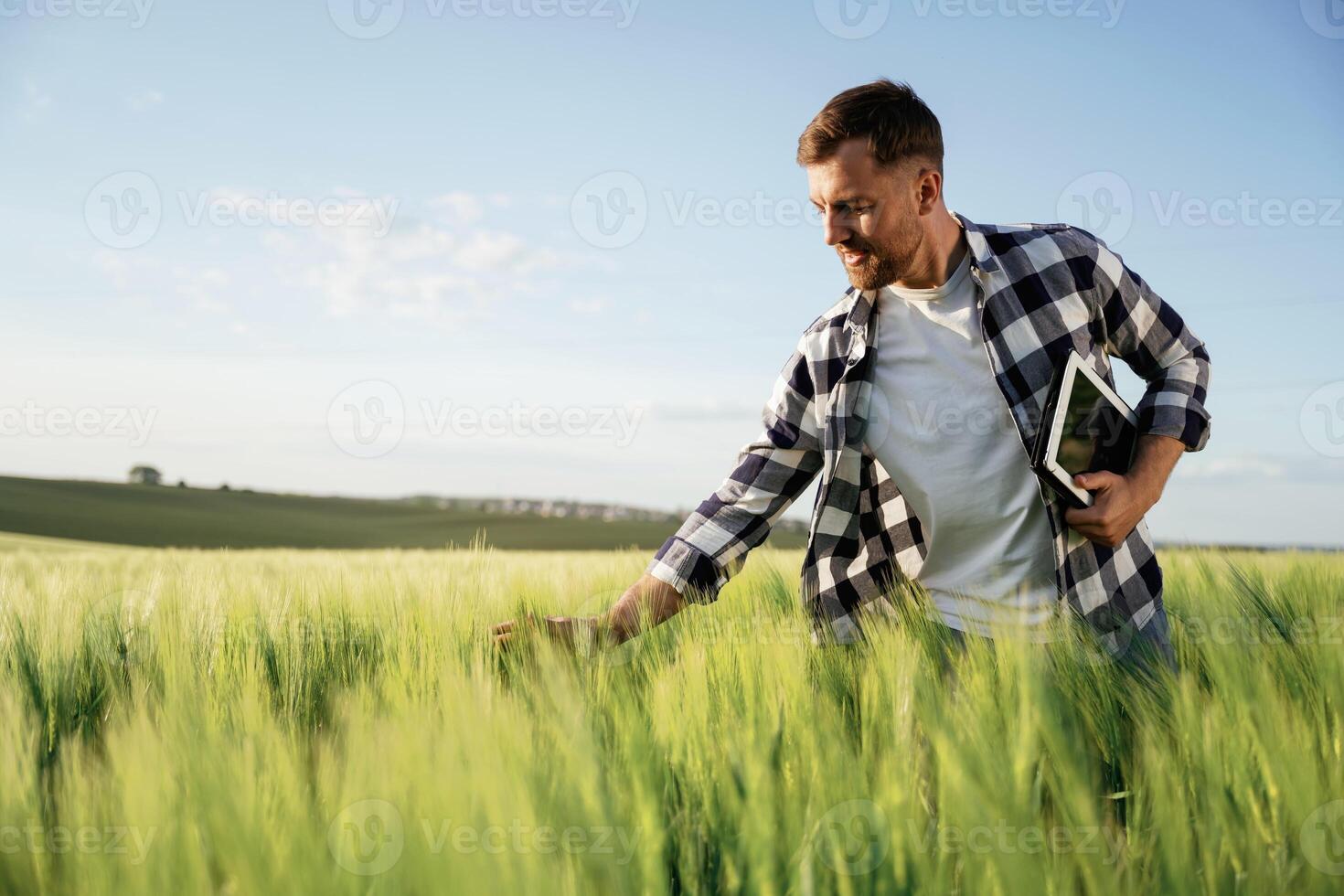 Black ,digital tablet in hands. Handsome man is on the agricultural field at daytime photo