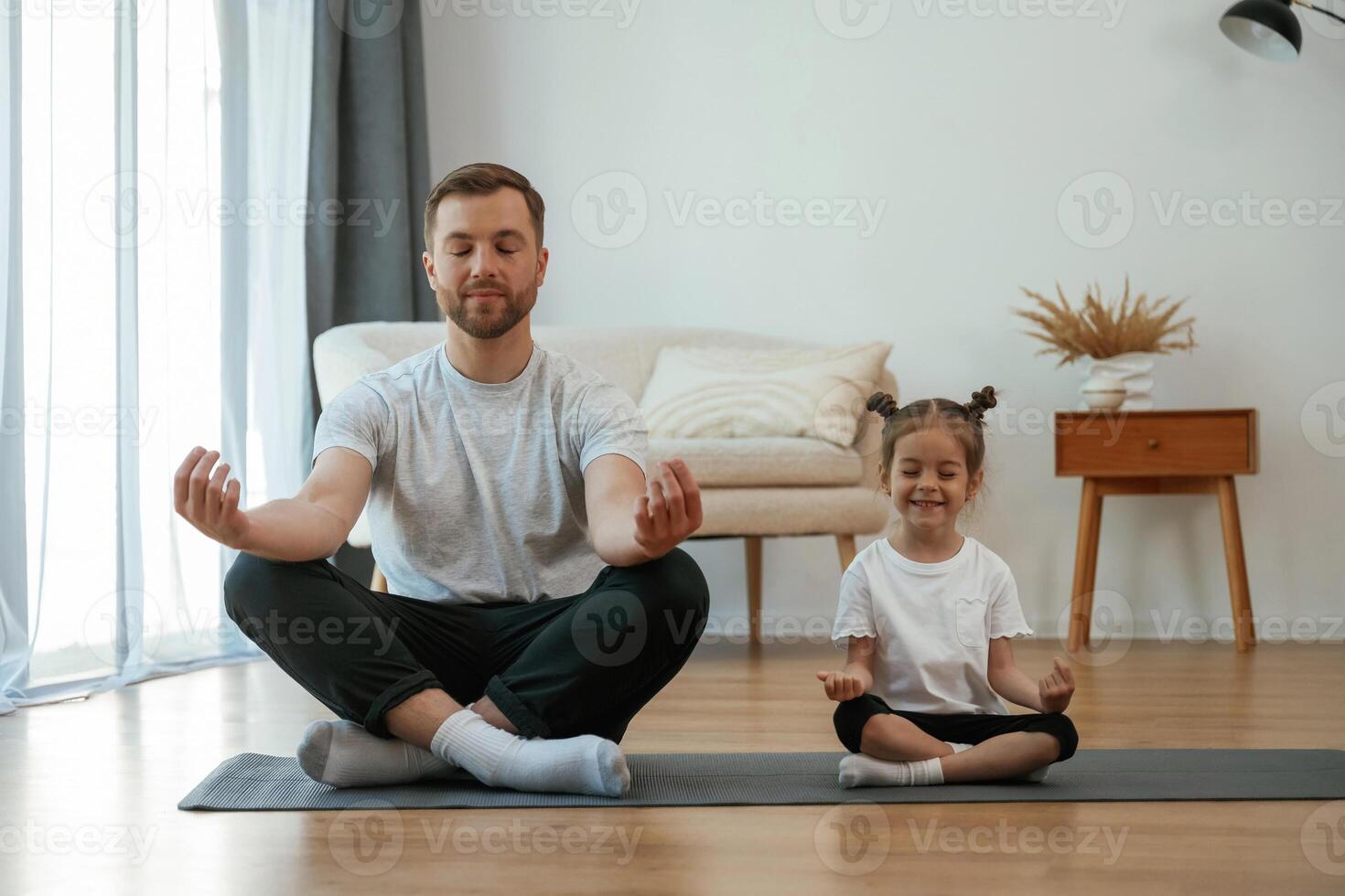 Lotus pose. Father with little daughter, are ,ing yoga at home photo