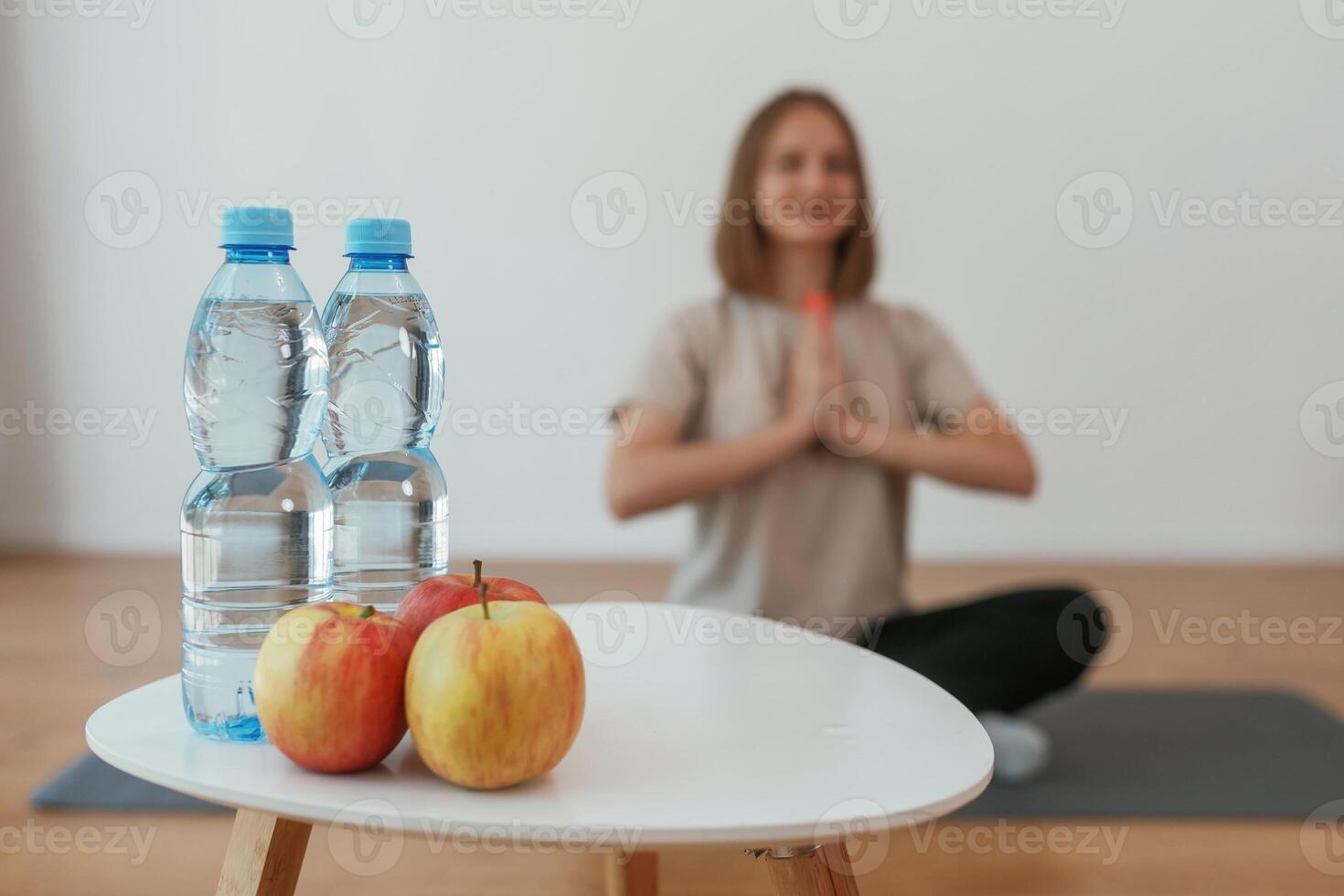 Young woman, is, sitting on the yoga mat. Conception of healthy eating, apples photo