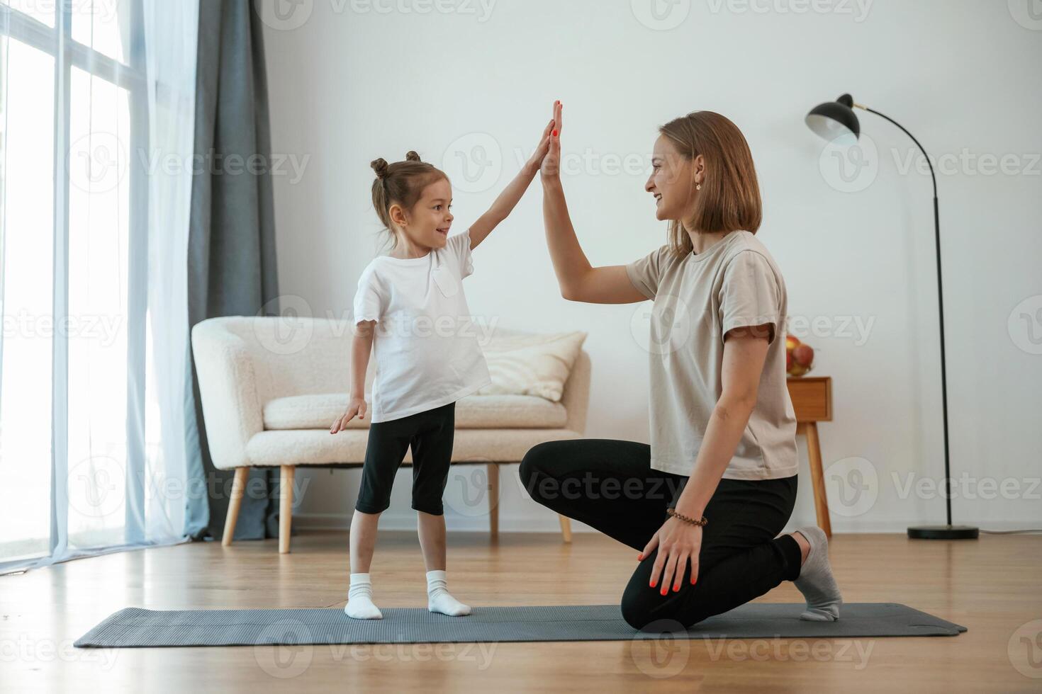 Well ,done, doing high five. Young woman with little girl are doing yoga at home photo