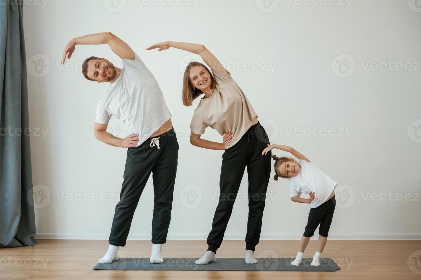 Warm up ,exercises. Family of mother, ,father and daughter are doing yoga at home photo