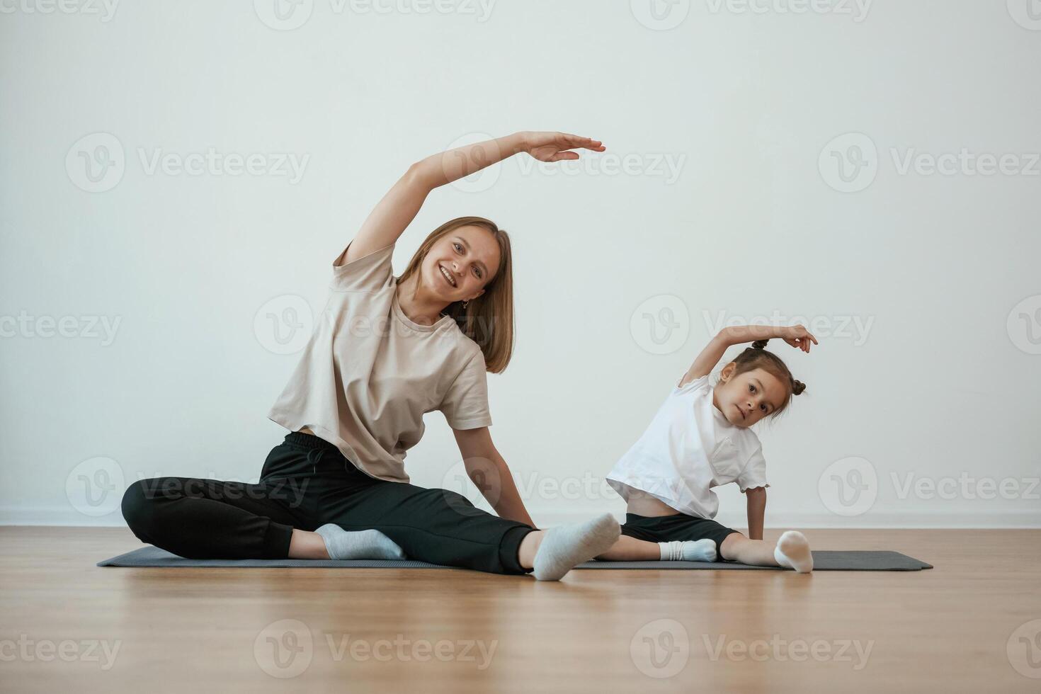 Young woman, with, little girl are doing yoga at home photo