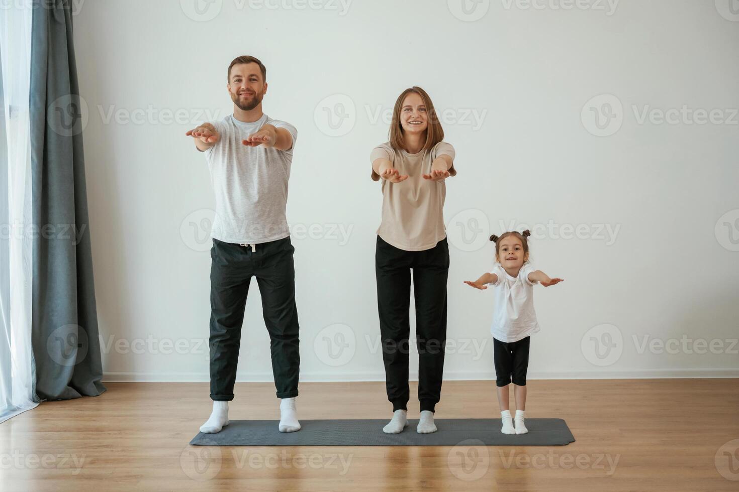 Warm ,up ,exercises. Family of mother, father and daughter are doing yoga at home photo