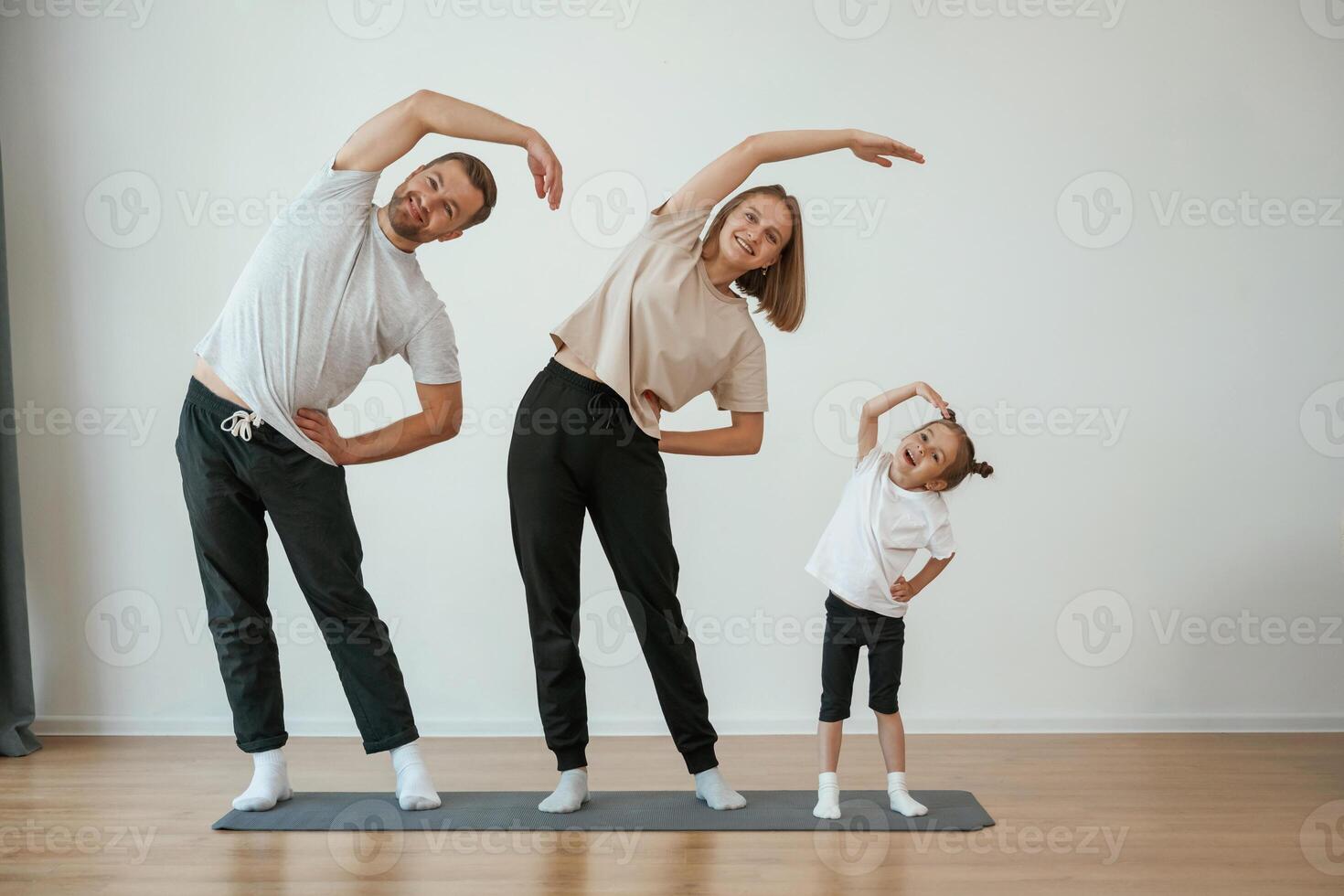 Warm ,up exercises. Family of mother, father and daughter are doing yoga at home photo