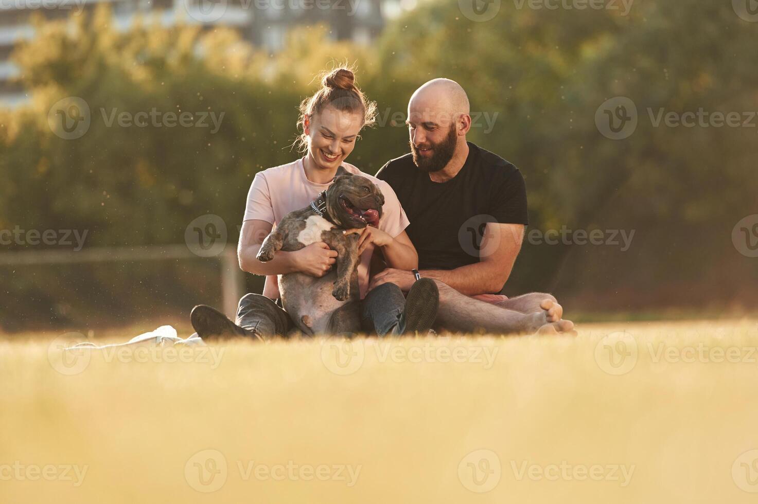 Having ,,a rest, sitting. Man and woman ,are with dog on the field photo