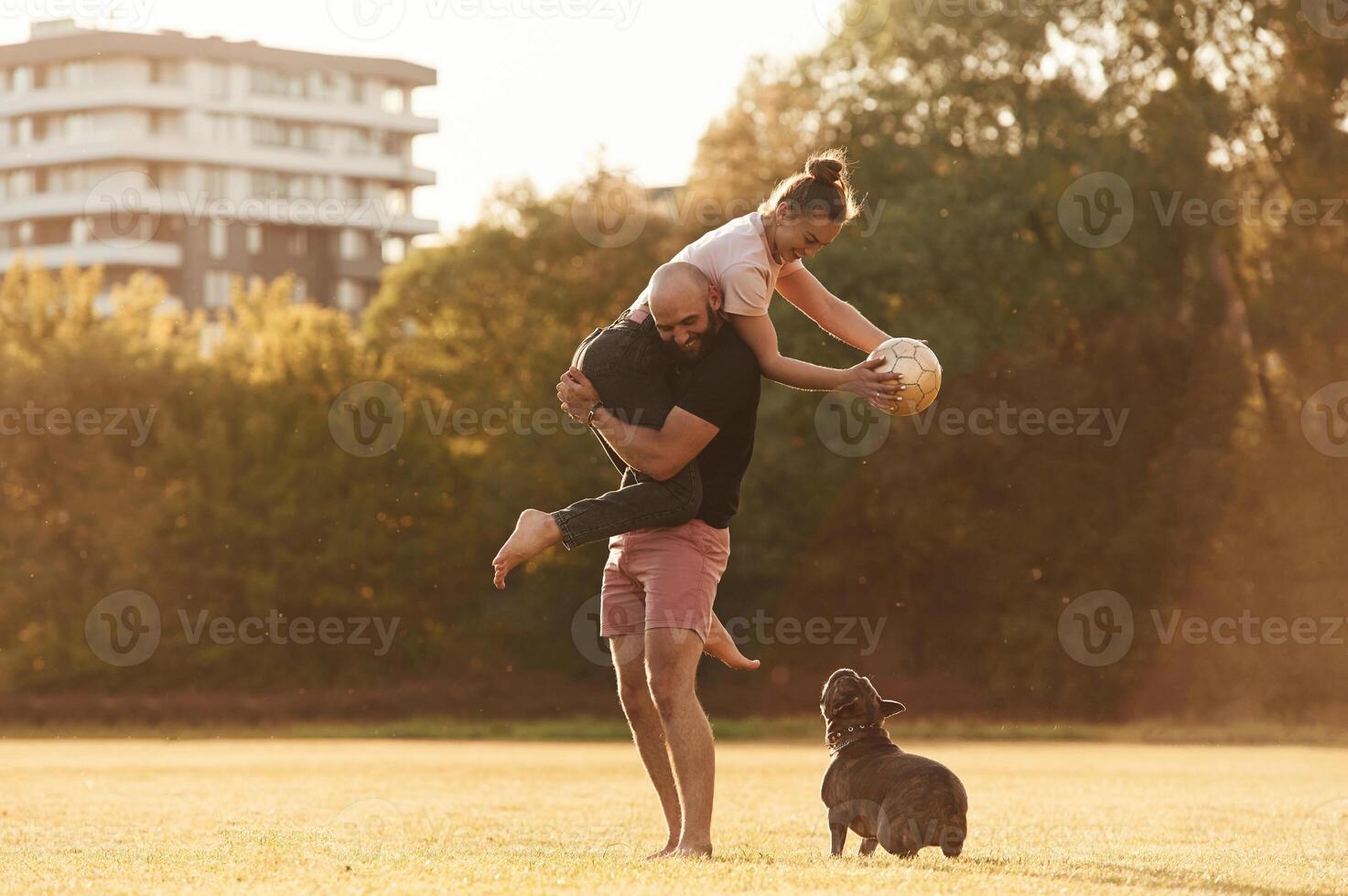 Girlfriend is with soccer ball. Man and woma,n are with dog on the field photo