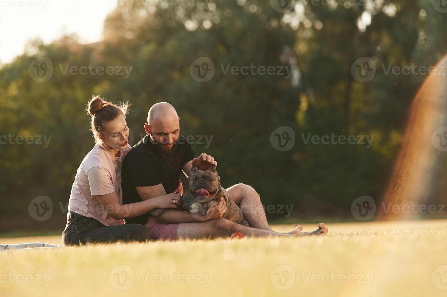 Weekend time, resting and sitting... Man and woman are with dog on the field photo