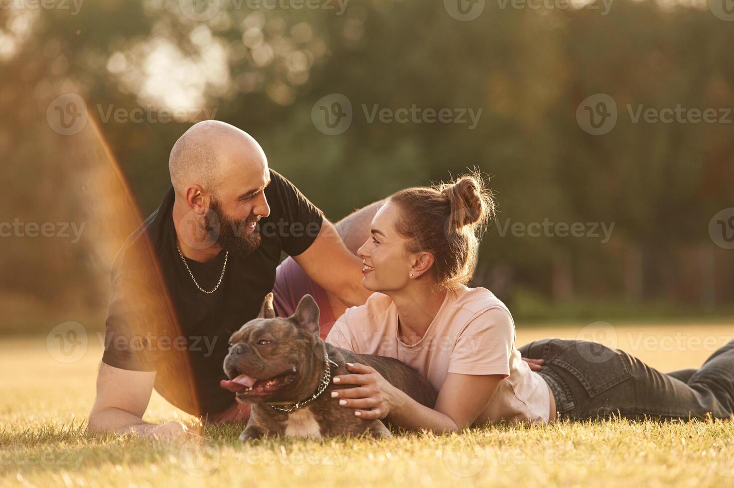 Positive facial,, expression, resting. Man and woman are with dog on the field photo