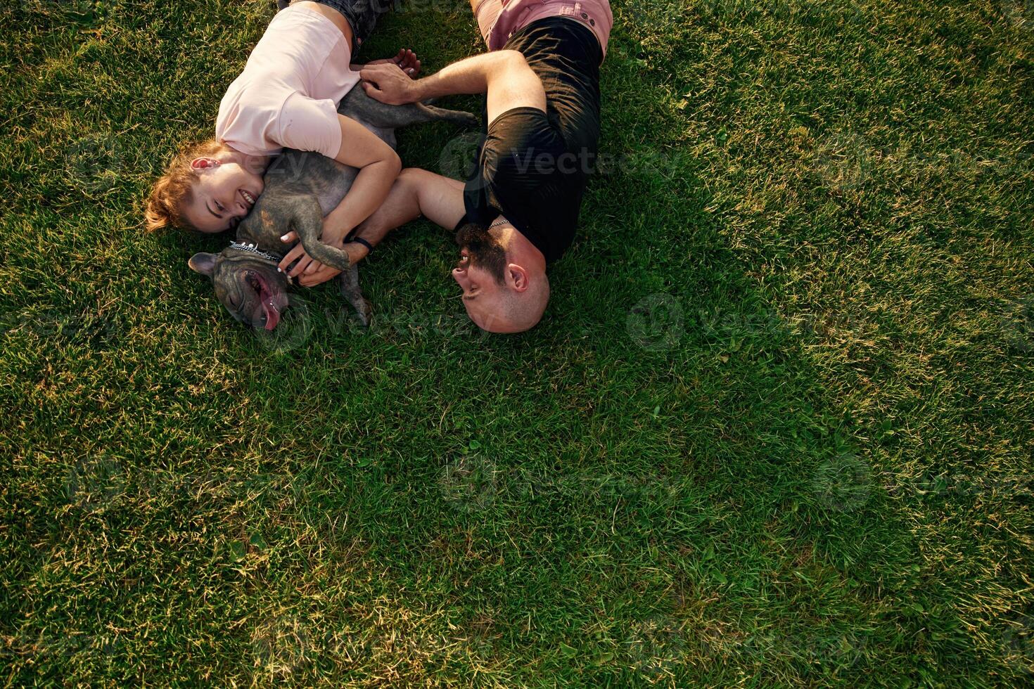 Top, view, lying ,on the grass. Man and woman are with dog on the field photo