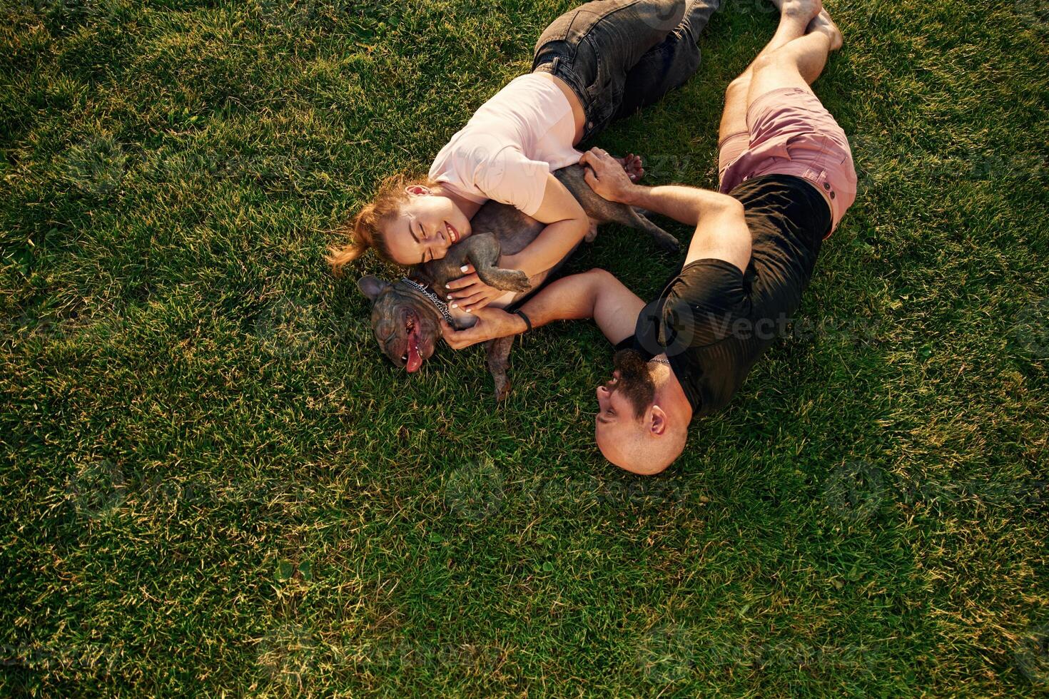 Top view,, lying on the grass. Man and woman are with dog on the field photo