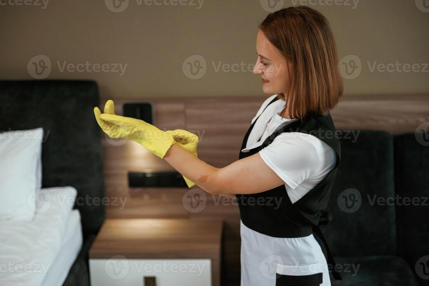 Wearing ,the, yellow gloves. Young chambermaid is in hotel room photo