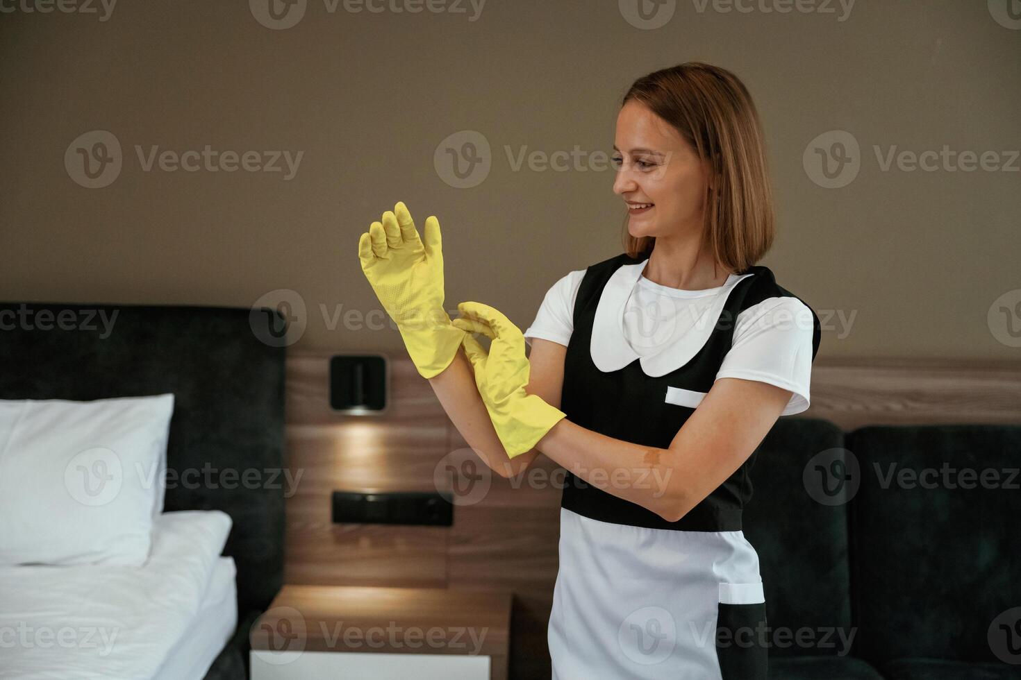 Wearing the, yellow gloves. Young chambermaid is in hotel room photo