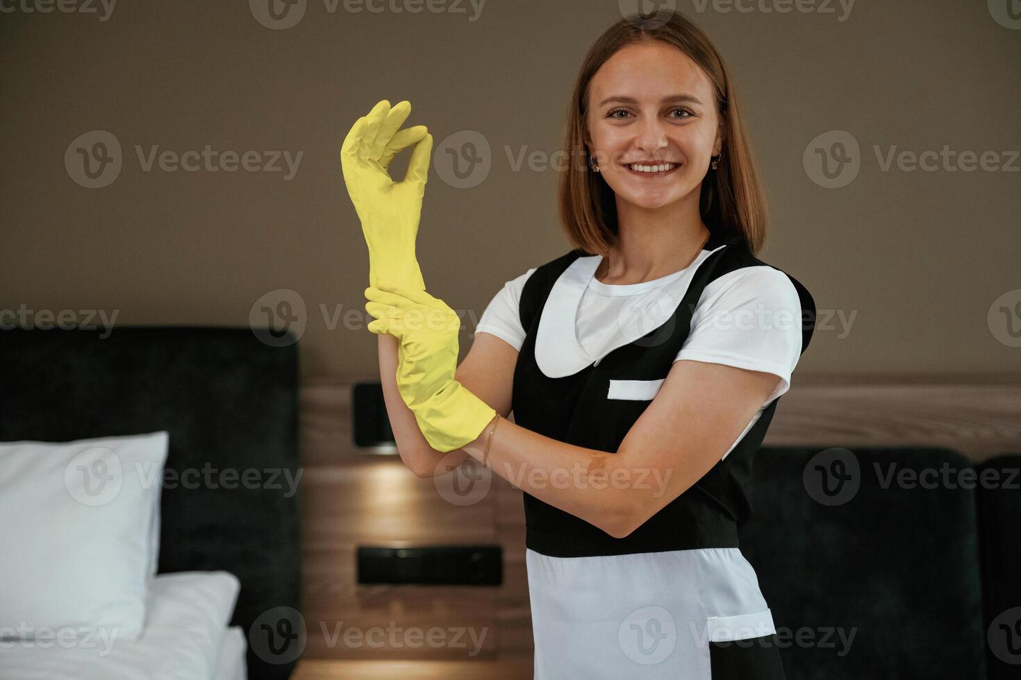 Cleaning, is finished, in yellow gloves. Young chambermaid is in hotel room photo