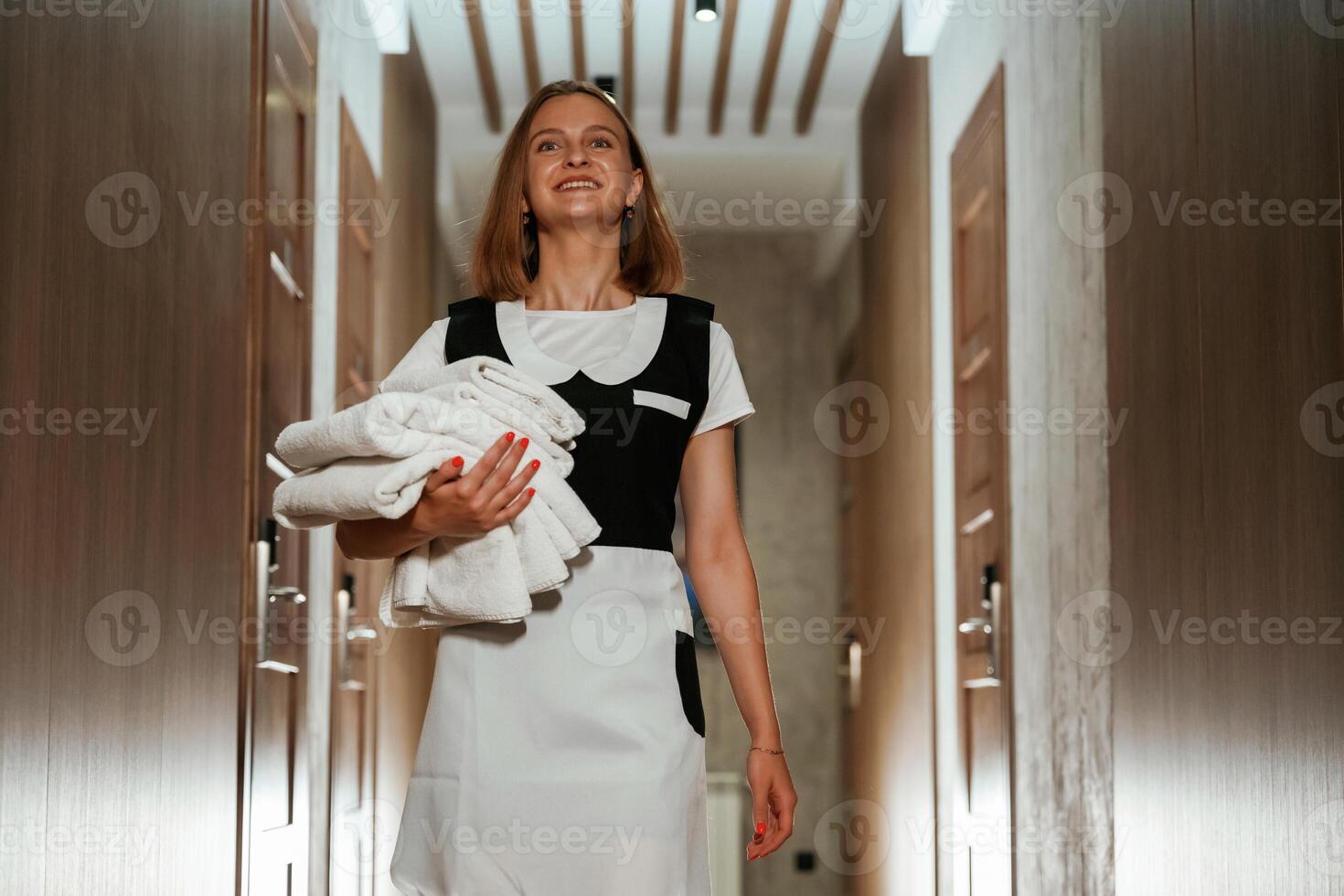 Holding, fresh, cloth for bed. Chambermaid is standing in the hotel corridor photo