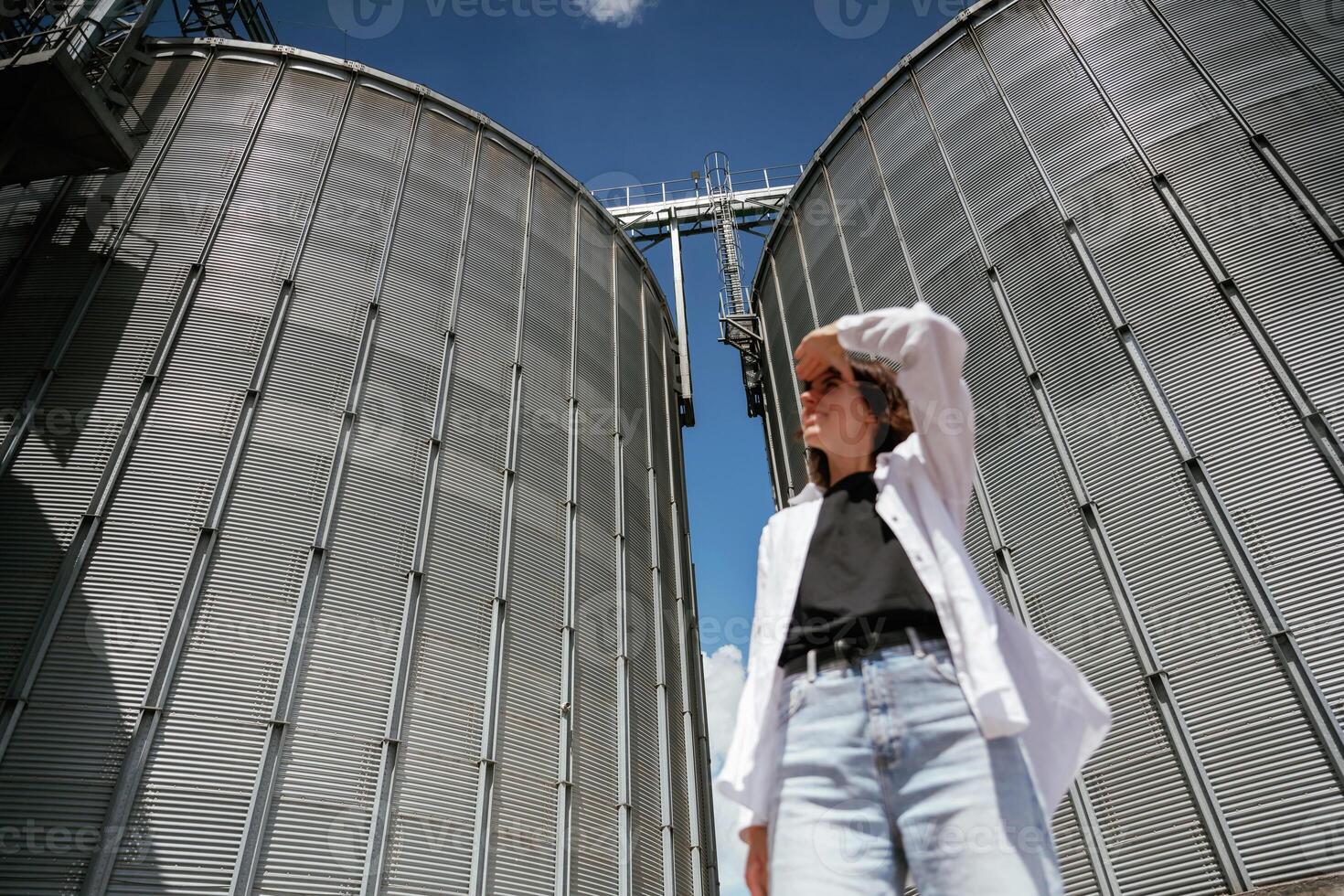 Looking far away. ,.Confident worker standing in front of industrial silos under clear blue sky photo